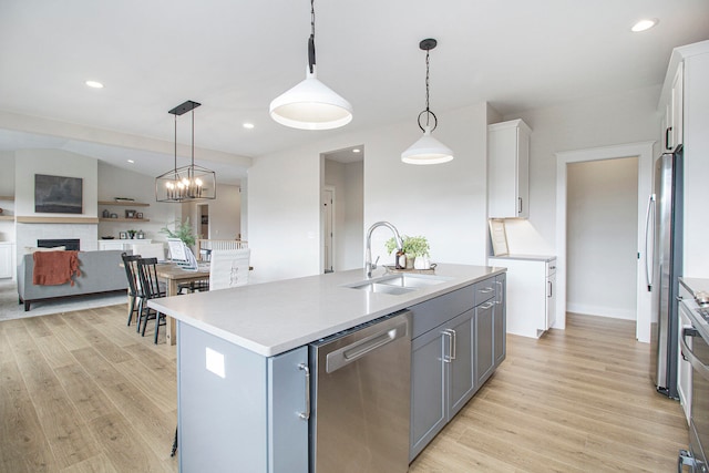 kitchen featuring light hardwood / wood-style flooring, stainless steel appliances, sink, hanging light fixtures, and white cabinets