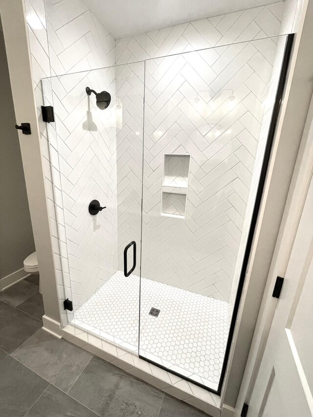 bathroom featuring an enclosed shower, tile patterned flooring, and toilet