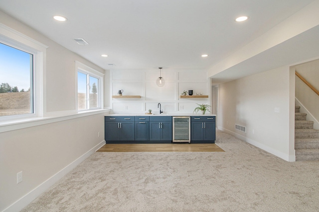 kitchen featuring light colored carpet, pendant lighting, wine cooler, and sink