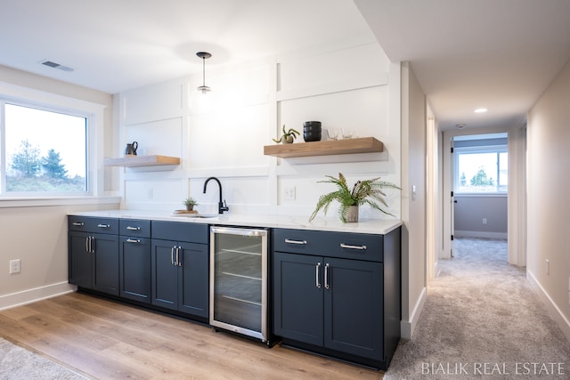 bar with light hardwood / wood-style flooring, sink, wine cooler, pendant lighting, and blue cabinets