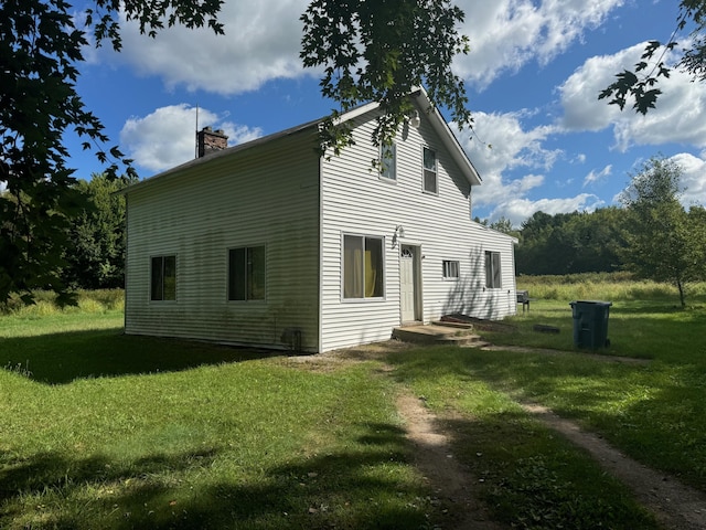 view of side of home with a lawn and a chimney