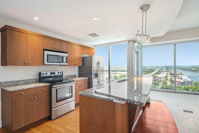 kitchen with brown cabinets, a kitchen island, pendant lighting, and stainless steel appliances