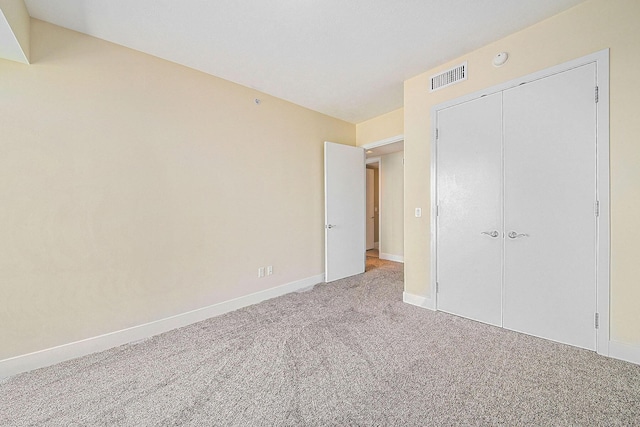 unfurnished bedroom featuring carpet floors, baseboards, visible vents, and a closet