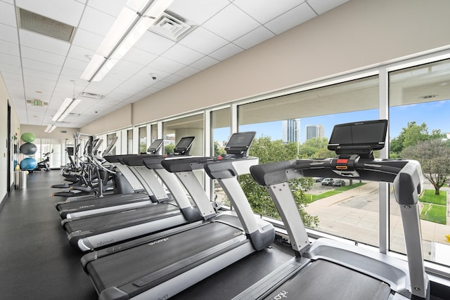 workout area with visible vents, a paneled ceiling, and a healthy amount of sunlight