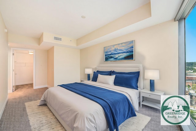 bedroom with light carpet, a walk in closet, visible vents, and baseboards