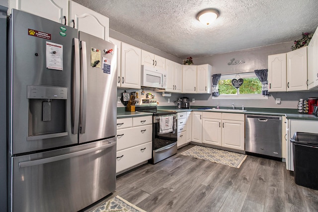 kitchen featuring appliances with stainless steel finishes, a textured ceiling, white cabinets, and dark hardwood / wood-style floors