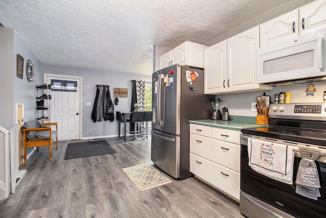 kitchen with appliances with stainless steel finishes, white cabinetry, wood-type flooring, and a textured ceiling