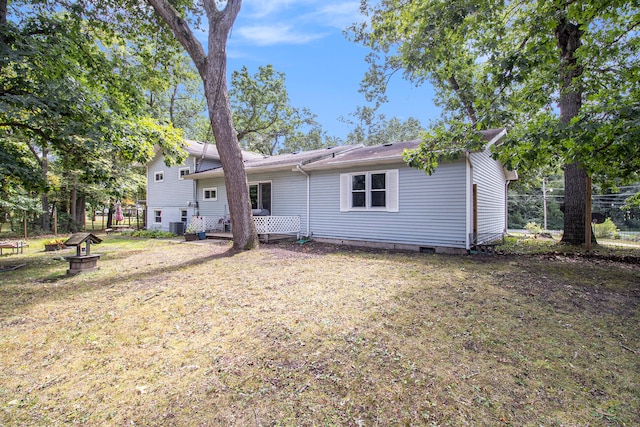 rear view of property featuring a lawn and central air condition unit