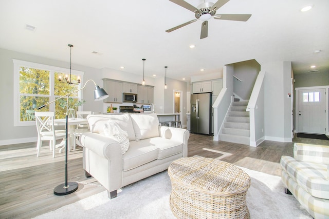 living area featuring recessed lighting, baseboards, stairway, and light wood finished floors