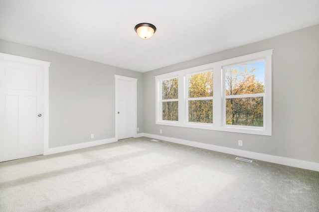 spare room featuring visible vents, baseboards, and light colored carpet