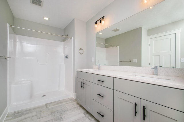 full bath with double vanity, visible vents, walk in shower, and a sink