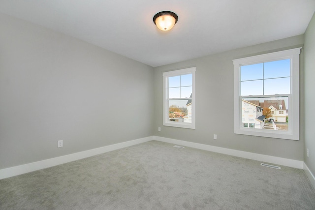 carpeted empty room with visible vents and baseboards