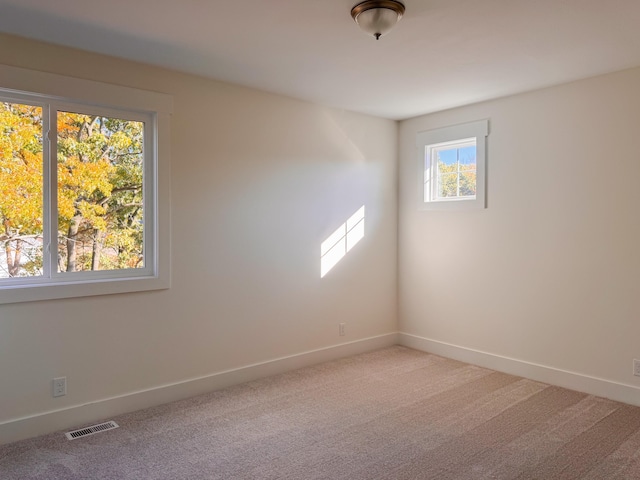 spare room with baseboards, visible vents, and light colored carpet