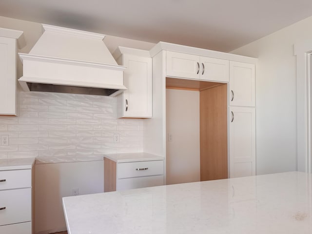 kitchen featuring premium range hood, white cabinetry, light stone countertops, and tasteful backsplash