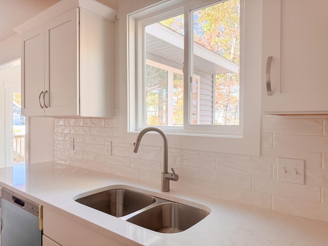 kitchen with a sink, white cabinets, decorative backsplash, and dishwasher