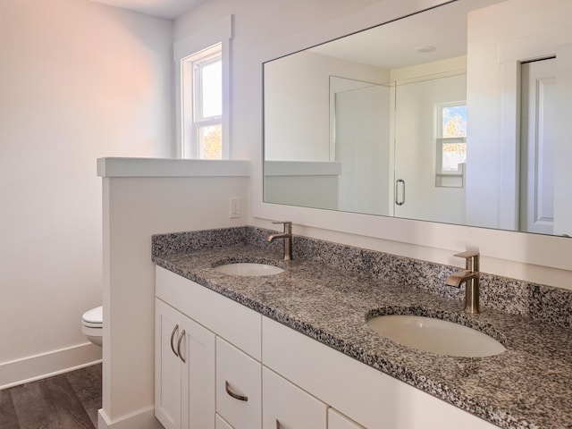 bathroom with toilet, a stall shower, baseboards, and a sink