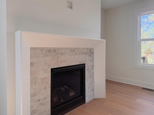 interior details with baseboards, a fireplace, visible vents, and wood finished floors