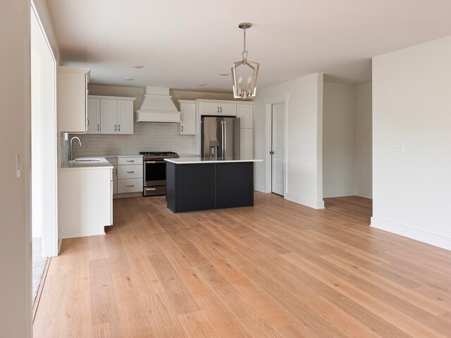 kitchen featuring stainless steel appliances, premium range hood, a sink, light wood-type flooring, and a center island