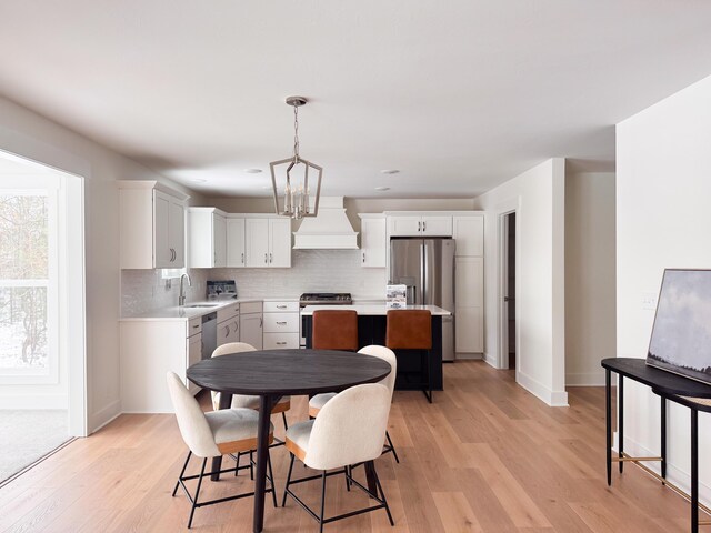 dining space featuring light wood-style floors, a notable chandelier, and baseboards