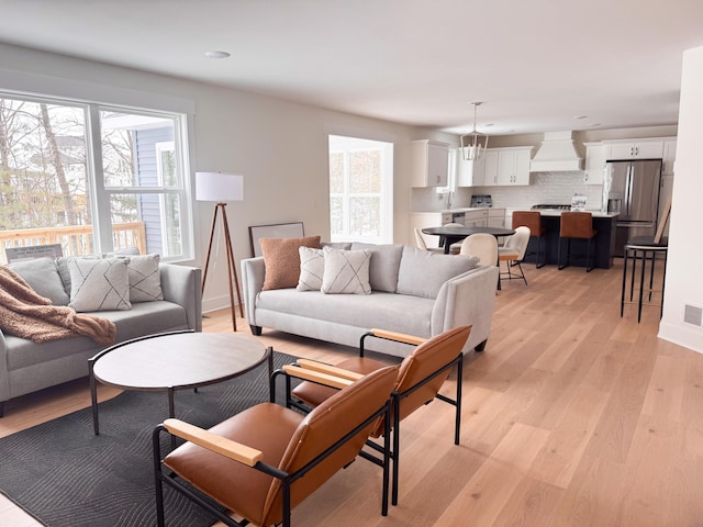 living room featuring light wood finished floors, baseboards, and visible vents