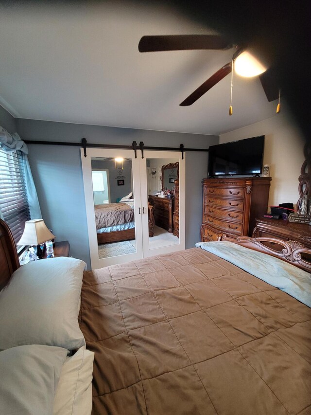 bedroom with a barn door and ceiling fan