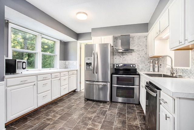 kitchen featuring white cabinetry, sink, decorative backsplash, wall chimney exhaust hood, and appliances with stainless steel finishes