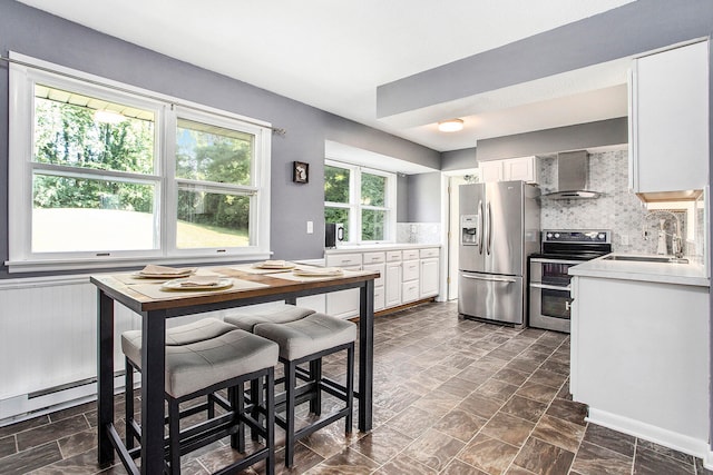 kitchen with white cabinets, stainless steel appliances, sink, wall chimney range hood, and tasteful backsplash