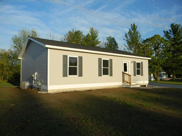 manufactured / mobile home featuring a front lawn and central AC unit