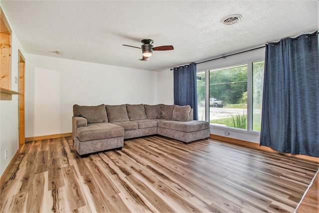 living room featuring hardwood / wood-style floors, ceiling fan, and a textured ceiling