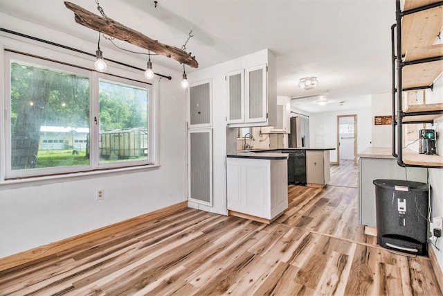 kitchen with light wood-type flooring, white cabinetry, stainless steel fridge, black dishwasher, and kitchen peninsula