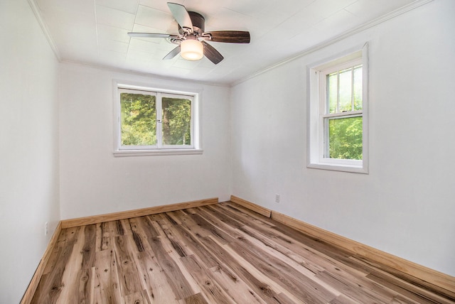 empty room with crown molding, wood-type flooring, ceiling fan, and a wealth of natural light