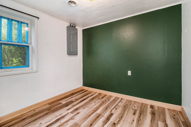 unfurnished room featuring hardwood / wood-style flooring, electric panel, and crown molding