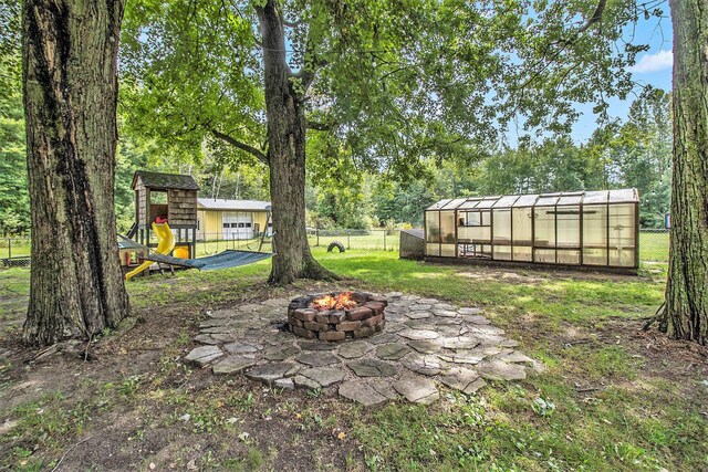 view of yard with a playground, a fire pit, and an outbuilding