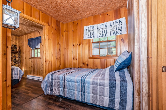 bedroom featuring dark wood-type flooring, baseboard heating, and wood walls