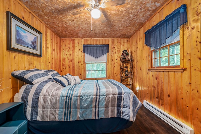 bedroom featuring dark wood-type flooring, baseboard heating, and ceiling fan