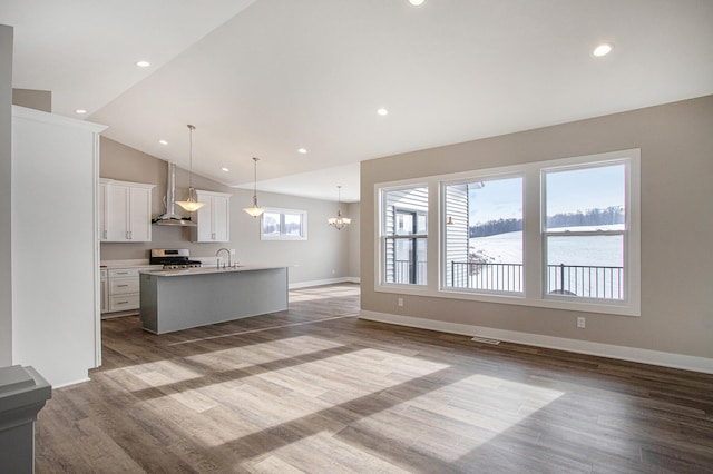 unfurnished living room with a water view, high vaulted ceiling, a notable chandelier, and light hardwood / wood-style flooring