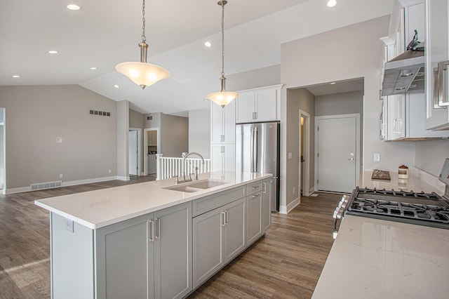 kitchen featuring hanging light fixtures, sink, lofted ceiling, dark wood-type flooring, and a center island with sink