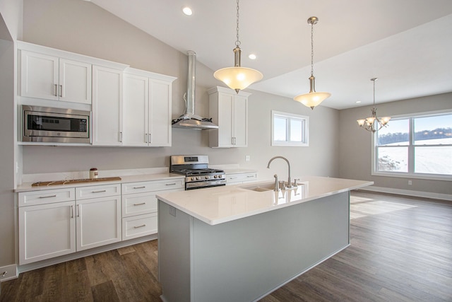 kitchen featuring decorative light fixtures, dark hardwood / wood-style flooring, sink, appliances with stainless steel finishes, and wall chimney range hood