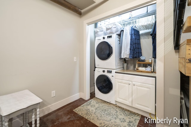 washroom with stacked washer / drying machine and cabinets