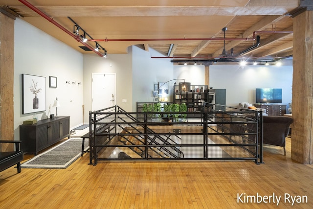 bedroom featuring beamed ceiling, hardwood / wood-style flooring, and rail lighting