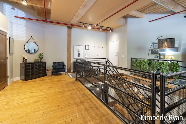 interior space featuring beamed ceiling, hardwood / wood-style floors, and rail lighting