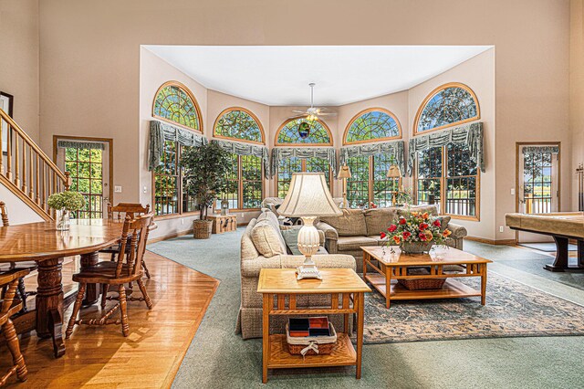 living room featuring ceiling fan, wood-type flooring, and a high ceiling