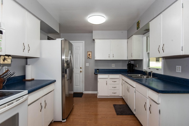 kitchen with white cabinets, wood-type flooring, white appliances, and sink