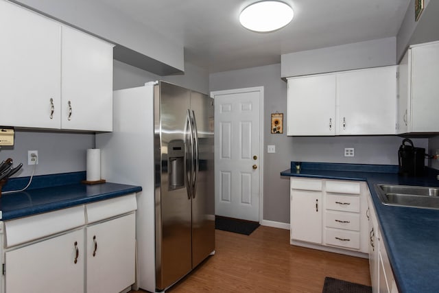 kitchen with white cabinets, dark hardwood / wood-style floors, stainless steel fridge, and sink