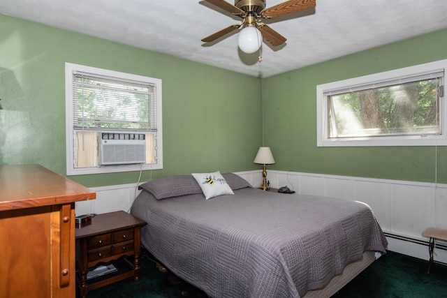 bedroom with dark colored carpet, baseboard heating, ceiling fan, and cooling unit