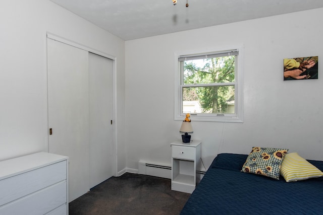 bedroom featuring a closet, a baseboard radiator, and dark colored carpet