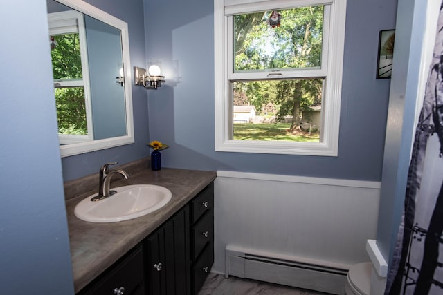 bathroom featuring a wealth of natural light, vanity, toilet, and baseboard heating