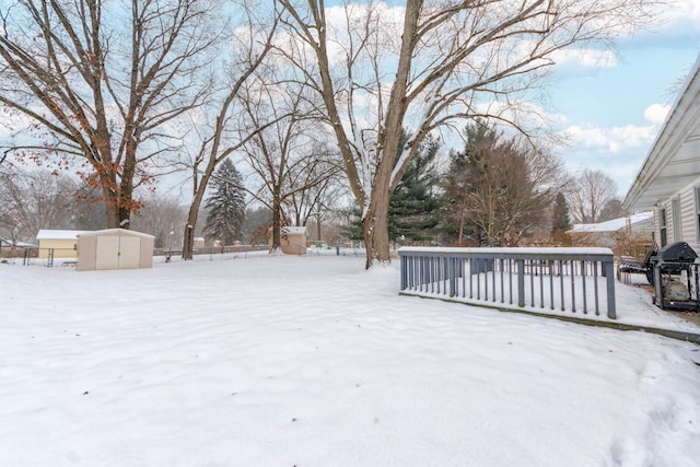 snowy yard with a storage unit and a wooden deck