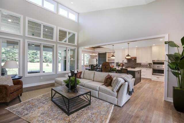 living room with a wealth of natural light, a high ceiling, sink, and light hardwood / wood-style floors