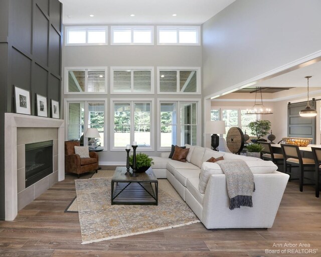 living room with a wealth of natural light, a high ceiling, a tiled fireplace, and hardwood / wood-style flooring